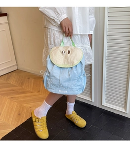 Dettaglio dello zaino in nylon azzurro con patta decorativa a forma di pera beige