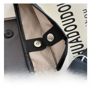 Détail de la boucle magnétique argentée et de la poche zippée sur un sac en toile