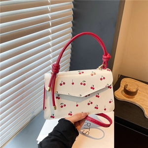 Ivory crossbody bag with red cherry print and red woven handle for summer fashion