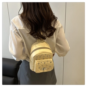 Cream quilted mini backpack with silver rivets and metal lock on model back