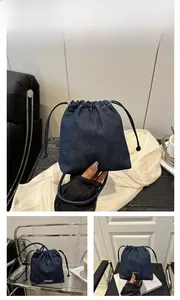 Detail view of dark blue denim drawstring bucket bag with JINGPIN metallic logo