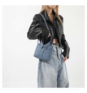 Vista dettagliata della borsa a tracolla azzurra con design a camicia e bottoni metallici