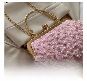 Detail of pink pearl lace clutch featuring 3D fabric roses and vintage gold hardware