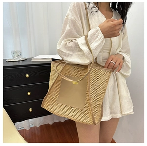 Detail of woven straw tote bag featuring leather patch and reinforced handles