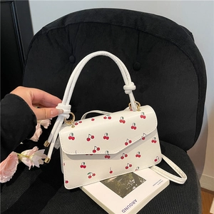 Fresh white crossbody bag with red cherry prints and golden metal hardware detail