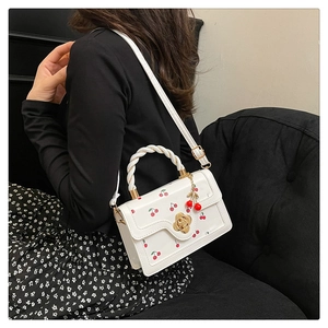 Detail of white cherry print purse with floral twist handle and golden flower lock