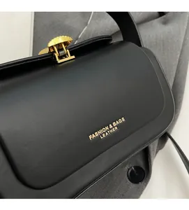 Detail of black leather crossbody bag with gold fashion logo and metallic hardware