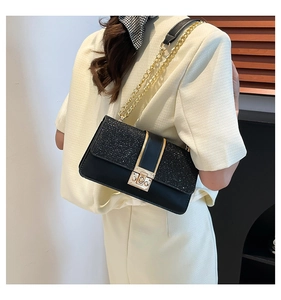 Detail of black sequined flap on women's chain bag with a gold letter G metal buckle
