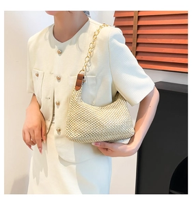 Detail of woven beige straw tote with gold chain strap and brown leather accents