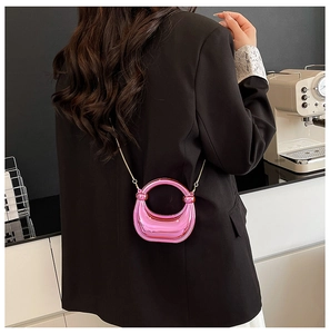 Detail of pink metallic mini chain bag on a black blazer with ring handle and gold chain