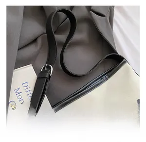 Détail de la bandoulière réglable en cuir noir et boucle argentée sur le cabas