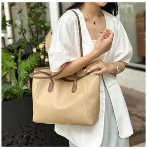 Chic beige tote bag with brown leather trim shown in a stylish urban street style photo