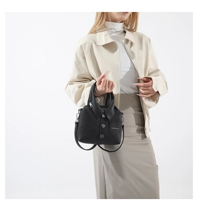 Detalle de bolso negro con forma de camisa con detalles de cuello y textura de cuero sintético