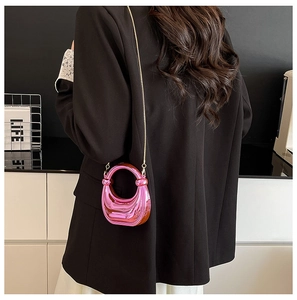 Chic rose pink metallic crossbody bag with circular hollow handle shown on a black blazer