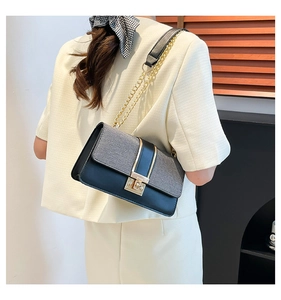 Detail of grey woven texture and black leather luxury crossbody bag with gold chain