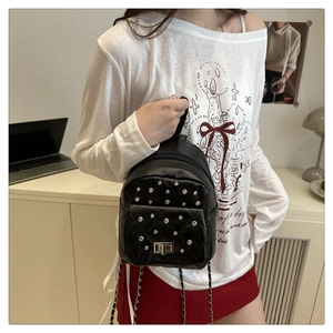 Close-up of black quilted leather backpack with silver rhinestones and chain strap