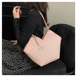 Close-up of pink monogram tote bag with gold M pendant worn by a model in lifestyle setting