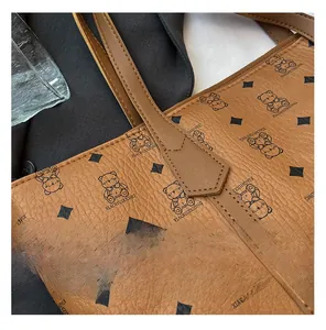 Close-up of brown pebbled leather tote featuring bear illustrations and diamond patterns