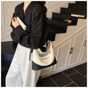 Détail du sac cabas en toile contrastée avec base en cuir et imprimé typographique