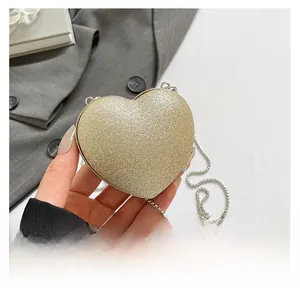 Dettaglio borsa a cuore glitterata dorata con sottile tracolla a catena in argento