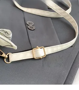 Detail of cream white leather strap with gold buckle and decorative geometric scarf