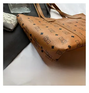 Close-up of brown textured leather tote bag with bear pattern and detailed stitching