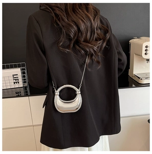 Silver mirror dumplings bag with chain strap shown on a model in a minimalist home setting