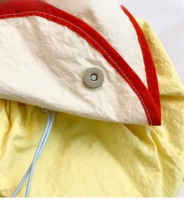 Close-up of the silver magnetic metal buckle and drawstring on yellow nylon backpack