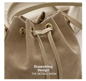 Detail view of the drawstring bucket bag showing its matte suede texture and gold eyelets