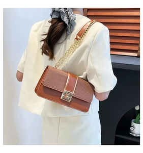 Detail of a brown patchwork chain bag with a gold twist lock on a minimalist outfit