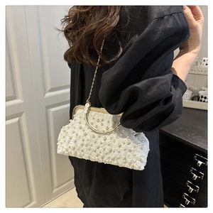 Detail of elegant white lace handbag featuring pearl embellishments and gold handle