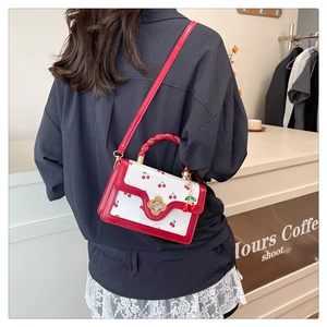 Vue détaillée d'un mini sac bandoulière à motif cerise avec fermoir doré et bandoulière rouge