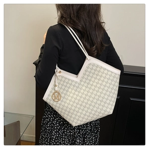 Détail du sac cabas ivoire avec jacquard à motif M et breloque en métal doré élégant