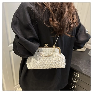 Detail of elegant shell bag with pearls, lace flower embroidery and gold ring handle