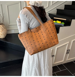 Brown leather tote bag featuring bear and diamond pattern worn by a model in a minimal room
