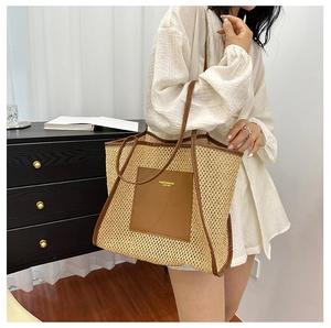 Close-up of woven straw tote bag with leather pocket and fine stitching detail