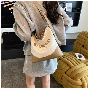 Détail d'un sac seau en toile avec bandoulière réglable porté par un mannequin