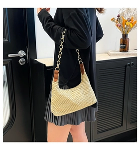 Detail of beige woven tote bag with gold chain strap and brown leather connectors
