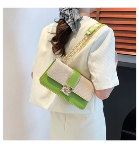 Detail of green leather and tweed patchwork crossbody bag with golden chain strap