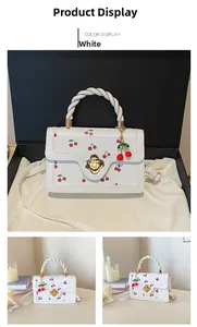 Close-up of white PU leather crossbody bag with cherry prints and golden flower lock