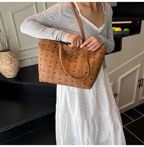 Detail of a large capacity brown tote bag with bear pattern worn by a model in a stylish setting