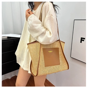 Close-up of woven straw tote bag with brown leather patch and golden logo detail