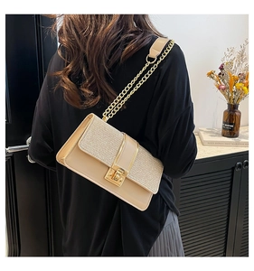 Detail of elegant beige chain bag with gold sequins shown from a side view on model