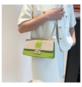 Detail of a chic green and beige woven crossbody bag with gold chain and rotating lock