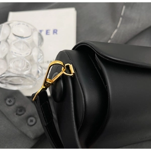 Detail of high-quality golden metal buckle and black leather strap on a stylish handbag