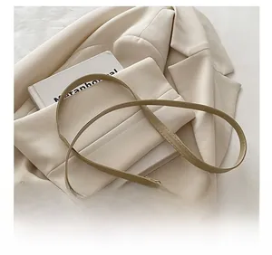 Detail of adjustable shoulder strap and gold hardware on beige bucket bag