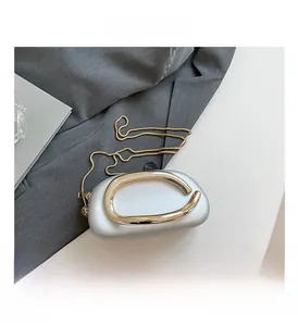 Silver pebble-shaped evening clutch featuring bold gold handle and elegant chain strap