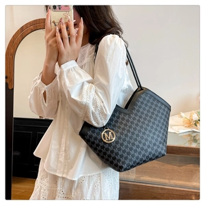 Détail du sac seau noir avec imprimé lettres M et pendentif doré en métal raffiné