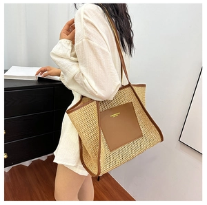 Detail of woven tote bag featuring a brown leather front pocket and sturdy top handles
