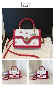 Detail of red cherry print handbag with floral lock and leather twisted handle